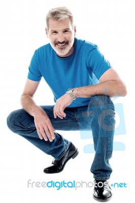 Handsome Man Crouching Down And Smiling Stock Photo