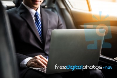 Handsome Young Businessman Using Laptop And Sitting In Back Seat… Stock Photo