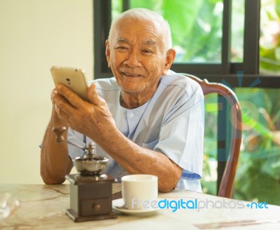 Happy Asian Senior Man Using The Mobile Phone In Home Stock Photo