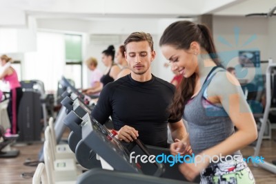 Happy Coach Assisting Young Woman In A Gym Stock Photo