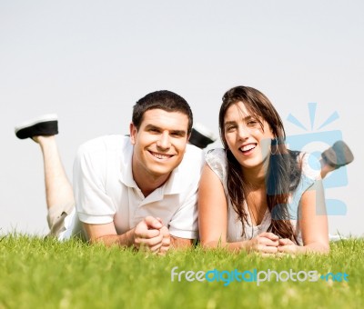 Happy Couple Lie Down On Grass Stock Photo