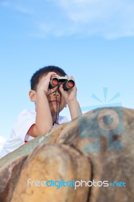 Happy Little Boy Exploring Outdoors Clambering On A Rock With Telescope Stock Photo