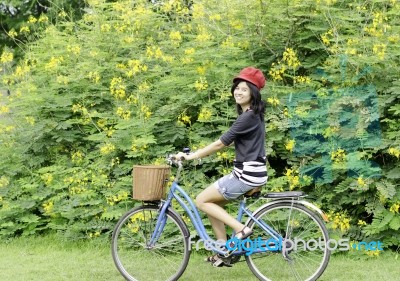 Happy Smiling Girl Riding A Bicycle In The Park Stock Photo