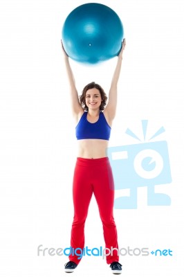 Happy Woman Lifting Pilates Ball Upwards Stock Photo