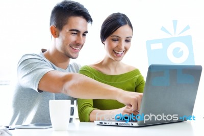 Happy Young Couple Browsing Internet At Home Stock Photo