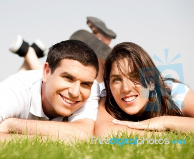 Happy Young Couple Lie Down On Grass Stock Photo