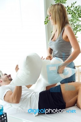 Happy Young Couple Playing With Pillows In The Sofa Stock Photo