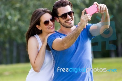 Happy Young Couple Taking Selfies With Her Smartphone In The Par… Stock Photo