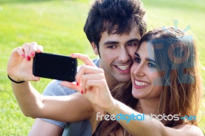 Happy Young Couple With Smartphone At The Park Stock Photo