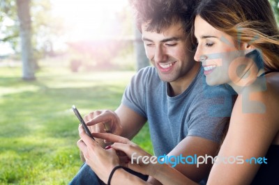 Happy Young Couple With Smartphone At The Park Stock Photo