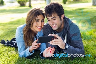 Happy Young Couple With Smartphone At The Park Stock Photo