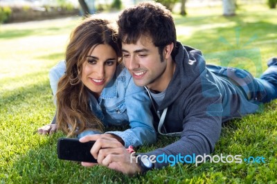 Happy Young Couple With Smartphone At The Park Stock Photo