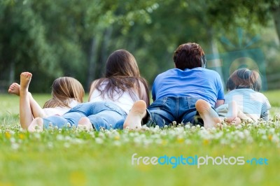 Happy Young Family Lying On Grass Stock Photo