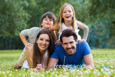 Happy Young Family Lying On Grass Stock Photo