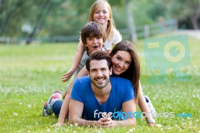 Happy Young Family Lying On Grass Stock Photo