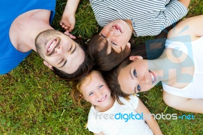 Happy Young Family Lying On Grass Stock Photo