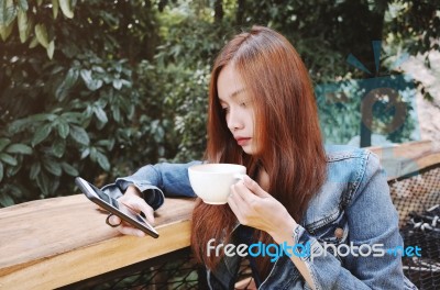 Happy Young Woman Drinking Coffee Outdoors And Using Smartphone Stock Photo