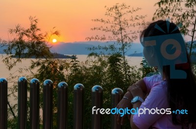 Happy Young Woman Standing Watching The Sunset Over The Lake Stock Photo