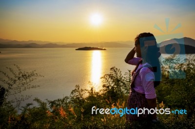 Happy Young Woman Standing Watching The Sunset Over The Lake Stock Photo