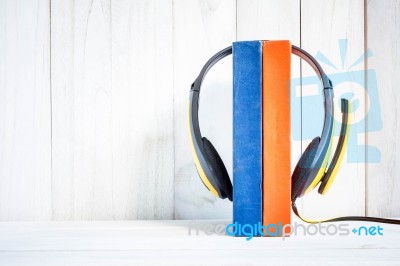 Headphones On Books On White Wood Background Stock Photo