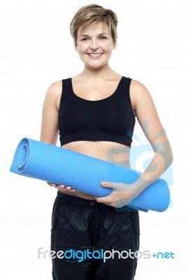 Health Conscious Woman Holding Blue Exercise Mat Stock Photo