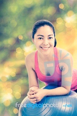 Healthy Woman - Girl Smiling And Leaning Fitness Ball, Blurred Bokeh Abstract Light Spring Forest Background Stock Photo