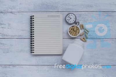 Herb Capsule With Blank Notebook And Vintage Watch Stock Photo