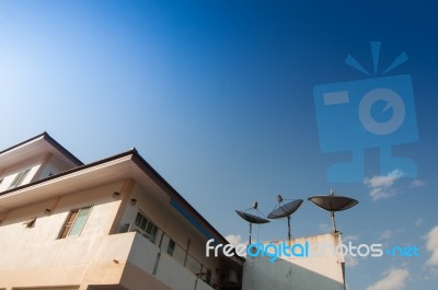 Home And Satlelite On A Roof With Blue Sky Stock Photo