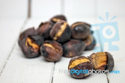 Hot Toasted Chestnuts On White Wooden Background Stock Photo