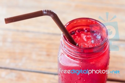 Iced Drink In Red Glass On Wooden Table Stock Photo