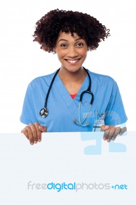 Joyous Female Doctor Standing Behind Ad Board Stock Photo