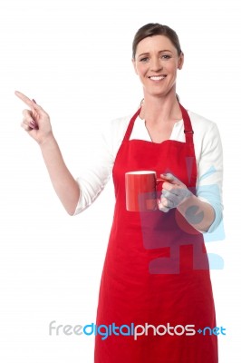 Joyous Female With Coffee Mug Pointing Away Stock Photo