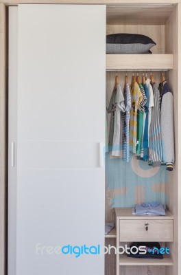 Kid's Clothes Hanging In White Wardrobe Stock Photo