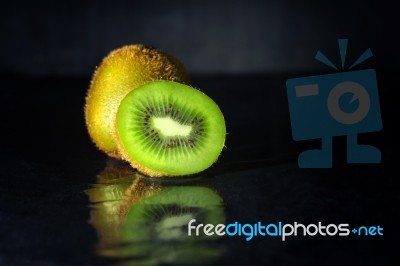 Kiwi Fruit On Black Stone With Water Reflection Low Key Light Stock Photo