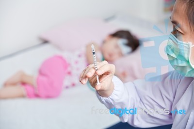 Lady Doctor Preparing An Injection For A Little Asian Girl Stock Photo