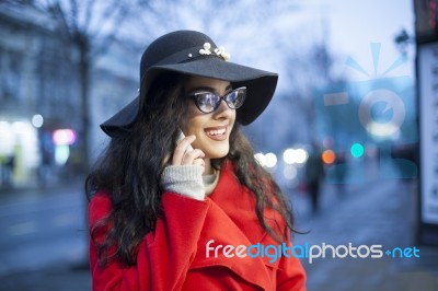 Lady In Red Coat With Smartphone In Hands Going Through The City… Stock Photo