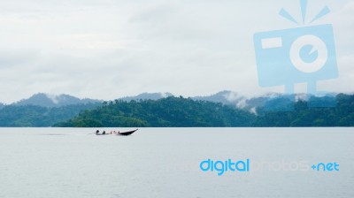 Landscape With Long Tail Boat Drive On Dam And Mountain Backgroud Stock Photo