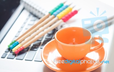 Laptop With Coffee Cup And Notepad On Desk Stock Photo