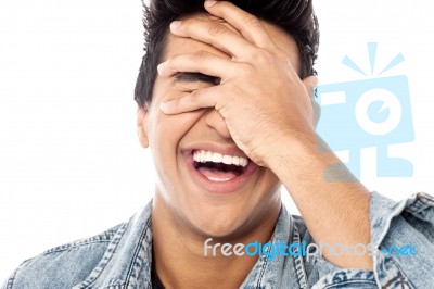 Laughing Young Man With Hand On His Face Stock Photo