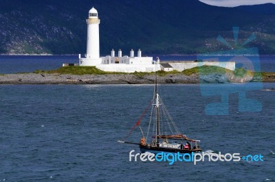 Lighthouse And Sailing Ship Stock Photo