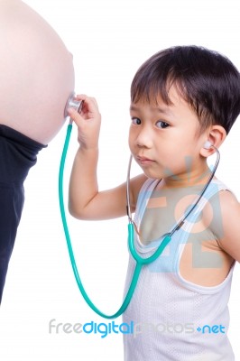 Little Asian Boy Examining Pregnant Mother's Tummy Stock Photo