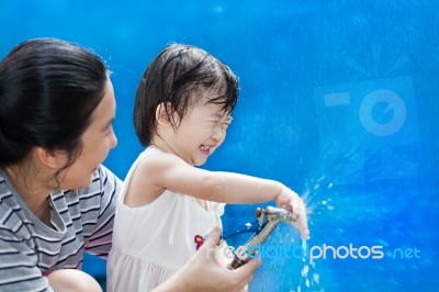 Little Asian Girl And Mother Play With Water Hose Stock Photo