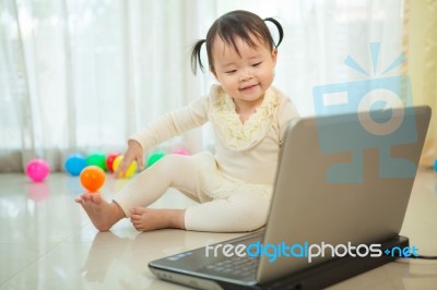 Little Asian Girl Play Laptop In Home Stock Photo