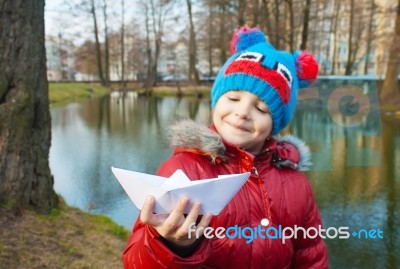 Little Girl Holding A Paper Boat Near The River Stock Photo