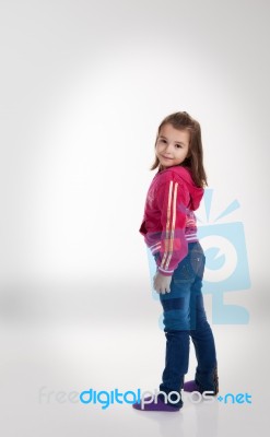 Little Girl In Blue Jeans And A Red Jacket In The Studio Stock Photo