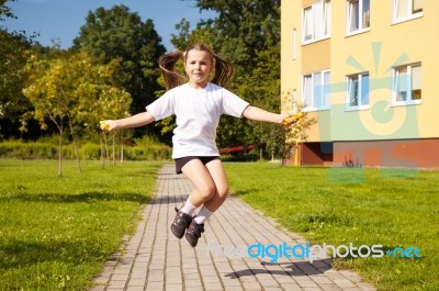 Little Girl Jumping Rope Outside Stock Photo