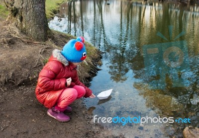 Little Girl Let A Paper Boat On The River Outside Stock Photo