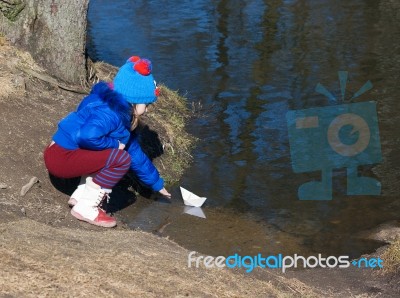 Little Girl Playing With Paper Boat On The River Stock Photo