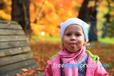 Little Girl Showes Tongue On Autumn Park Stock Photo