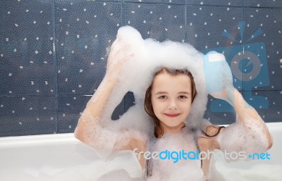 Little Girl Sitting In A Bath With Soap Suds On Her Head Stock Photo